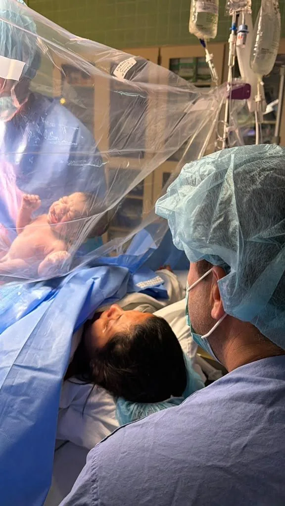 A newborn lifted up moments after a cesarean birth